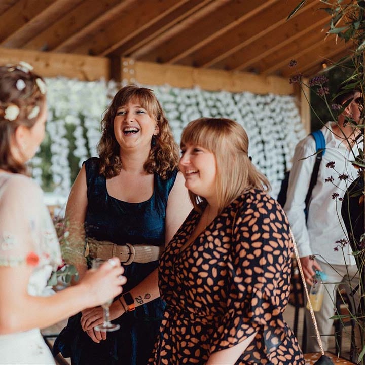 Bride with flowers in her hair socialises with wedding guests