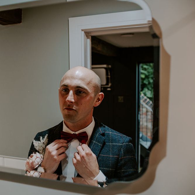 Groom wears red bow tie and tartan blazer complete with white shirt 