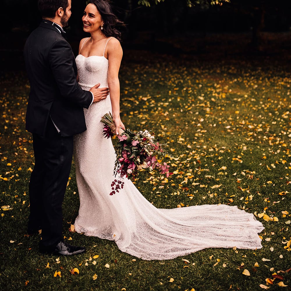 Gorgeous bride in a fitted beaded sparkle wedding dress from Made With Love smiling at the groom in black tie
