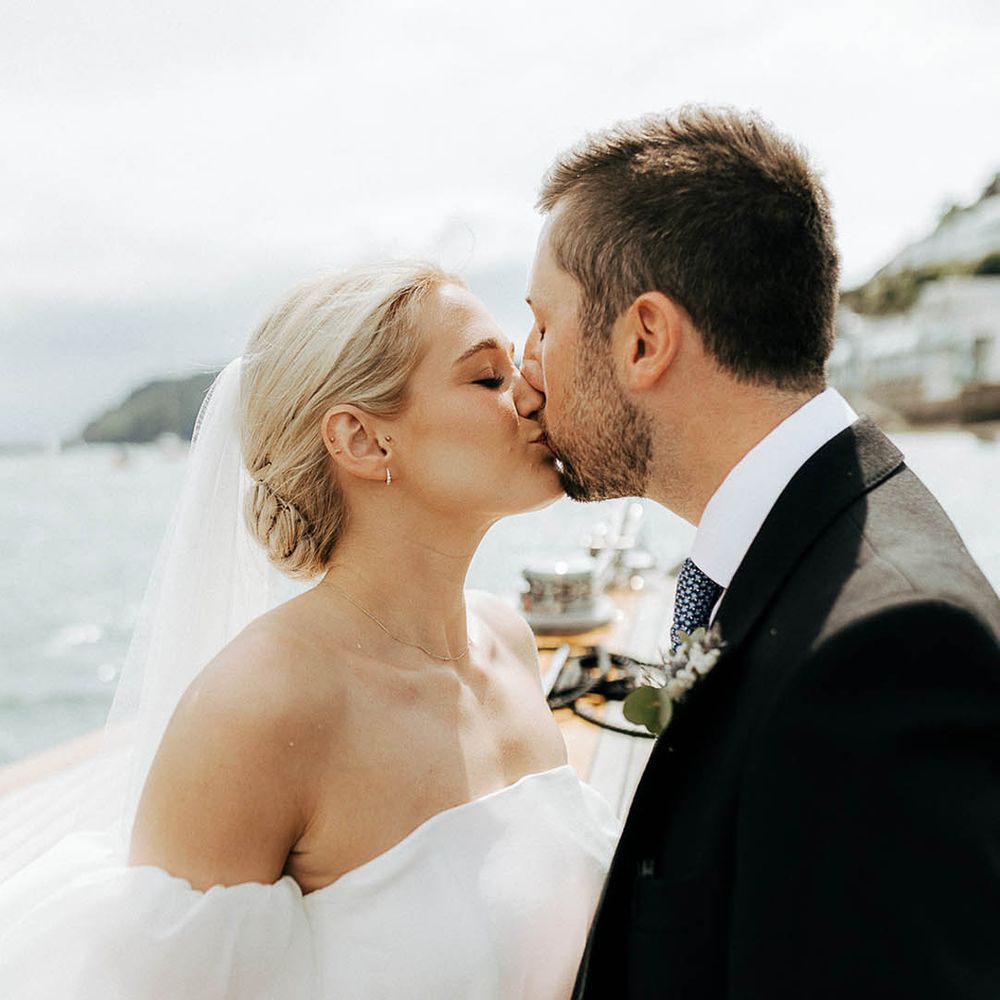 Bride with blonde hair and wearing Jesus Peiro wedding dress kisses her groom outdoors 