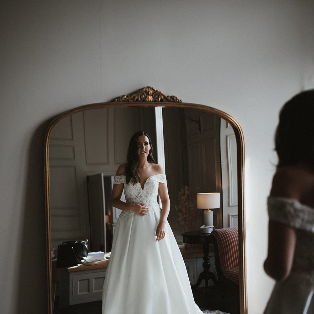 Bride in off the shoulder lace and princess skit wedding dress from Pronovias with her hair in soft waves 