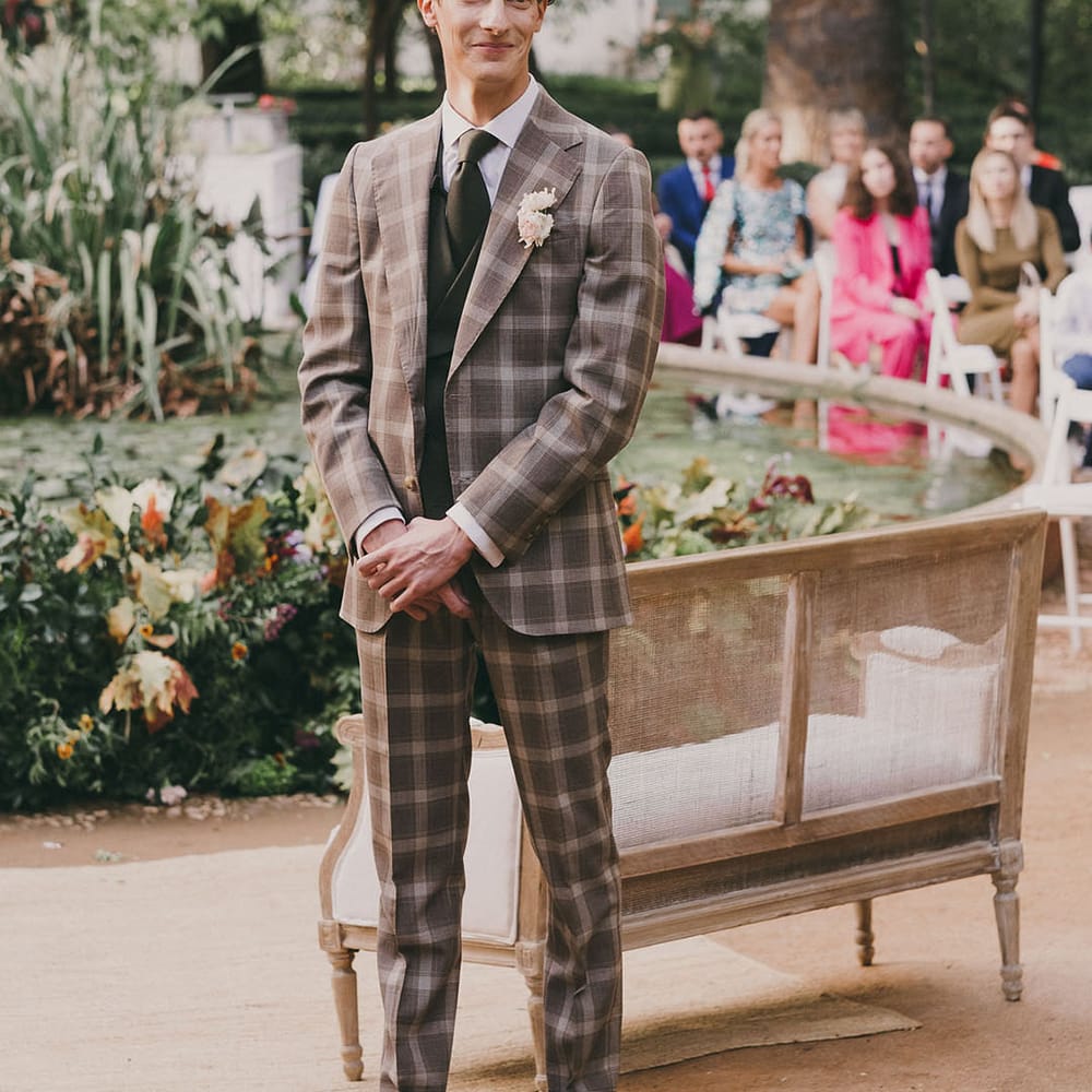 groom with curly hair in a grey check wedding suit 