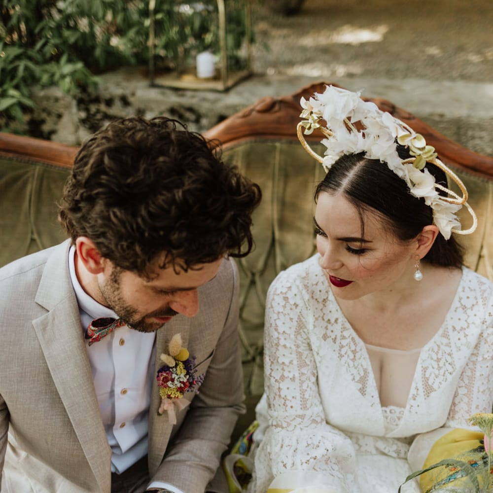 Bride in white floral bridal crown and red lip bridal makeup with groom in greige suit at outdoor wedding in Italy