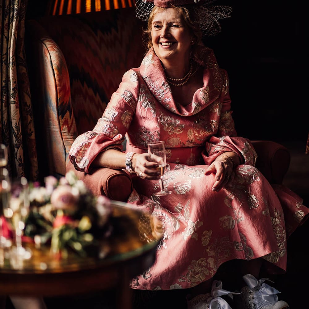 Mother of the bride wearing a pink dress with gold embroidery with vintage style blue wedding shoes 