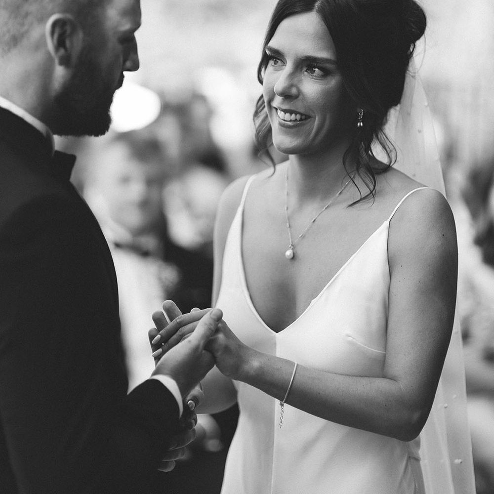 Bride holds hands with the groom at their outdoor wedding ceremony 