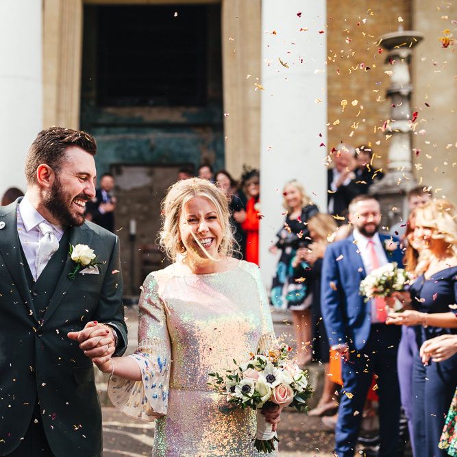 Bride & groom laugh together after marriage with confetti thrown around them