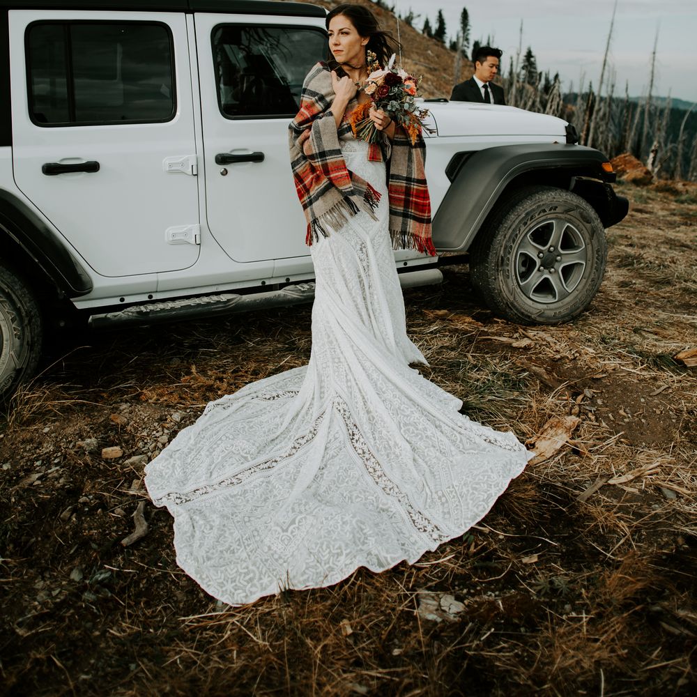 Bride stands in front of white wedding Jeep