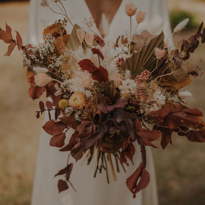 Autumn wedding bouquet with brown foliage, dried palm leaves and orange flowers 