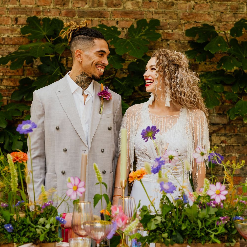 Bride and groom standing behind colourful wedding table decor and flowers at fiesta theme wedding