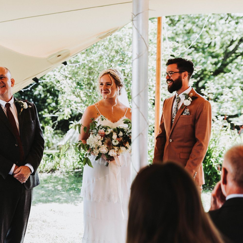 Bride & groom look toward brides father on wedding day