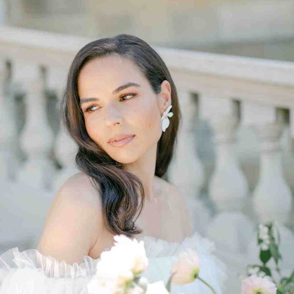 Beautiful bride with long brown hair in an off the shoulder wedding dress holding a pastel flower wedding bouquet 