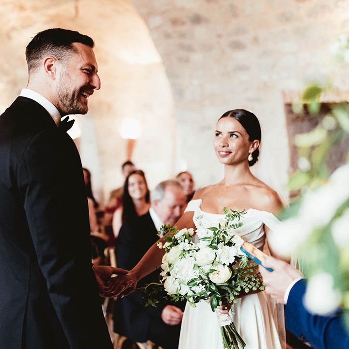 Bride looks lovingly at her groom as she wears her dark hair slicked back into low bun