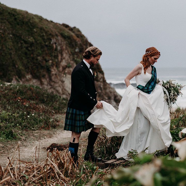 Groom in highland wear belong his bride in an a line wedding dress up the Big Sur mountain 