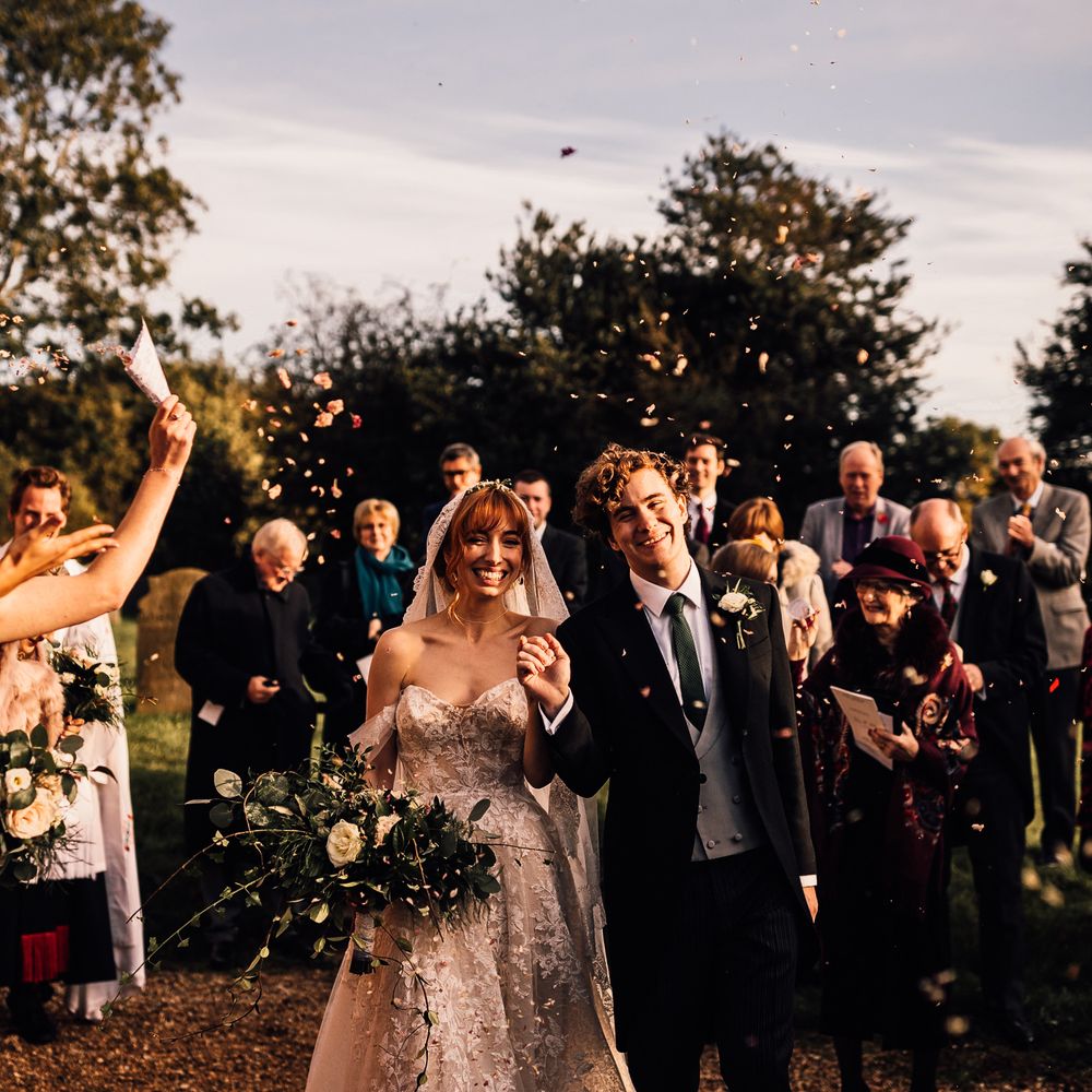Guests throw wedding confetti over bride and groom
