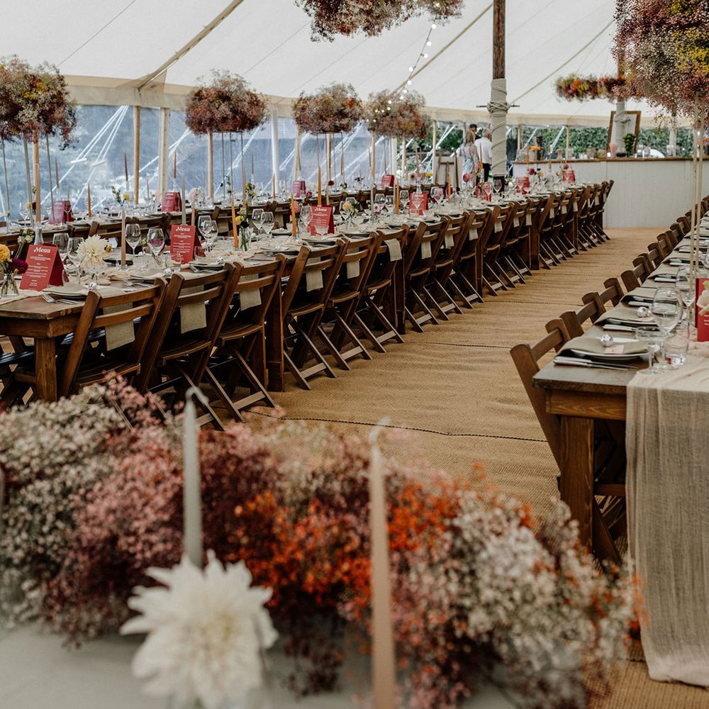 Stylish marquee wedding reception with hanging gypsophila flower clouds and tall centrepiece decor 