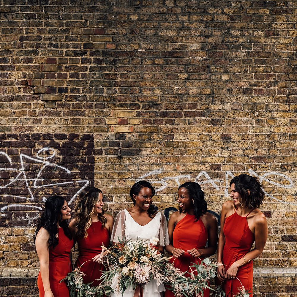 Bridal party with burnt orange bridesmaid dresses, hoop bouquets and bride in a layered tulle skirt and pearl top by Story Of My Dress 