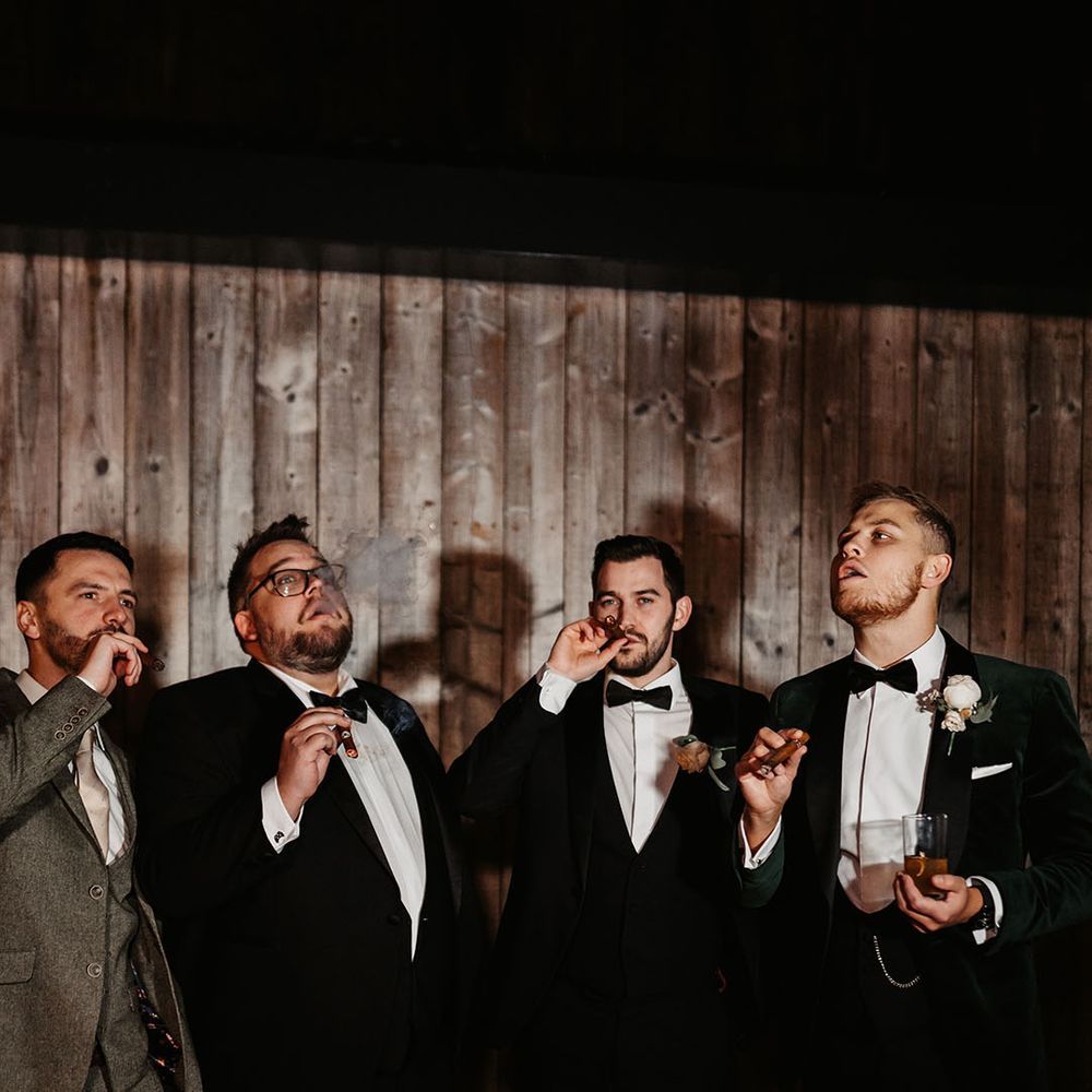 Groomsman take a puff from their cigars after winter wedding in the Lake District 