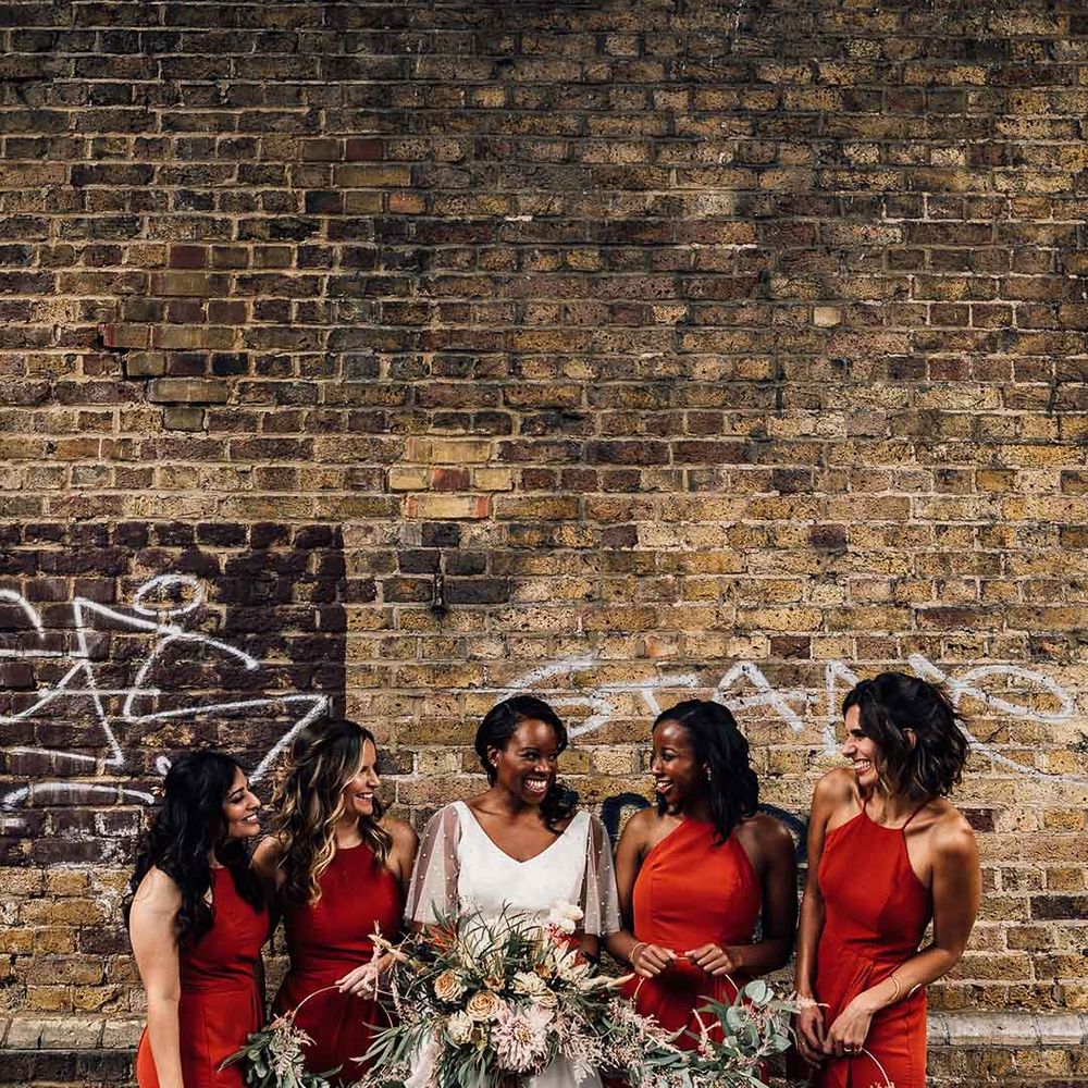 Bridal party in burnt orange bridesmaid dresses with mixed flower circle bouquets, bride in layered short sleeved dress 