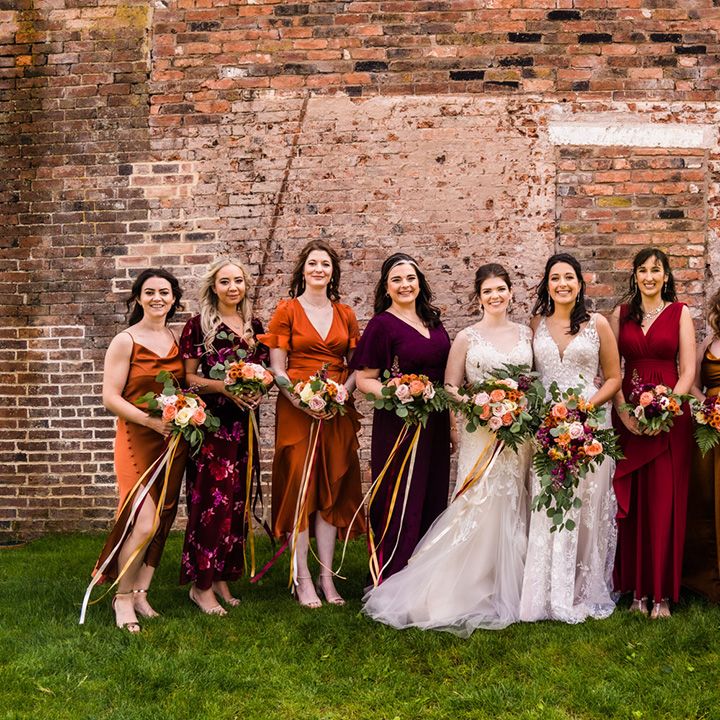 Bridal party with brides in lace wedding dresses and bridesmaids in jewel tone autumnal theme dresses
