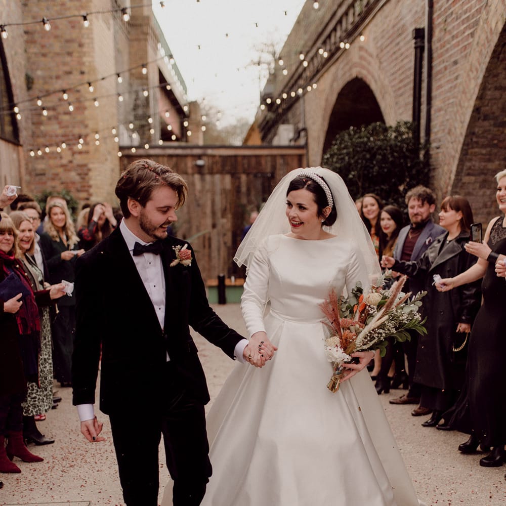 Newlyweds walk hand in hand together in front of wedding guests at LGBTQI+ wedding