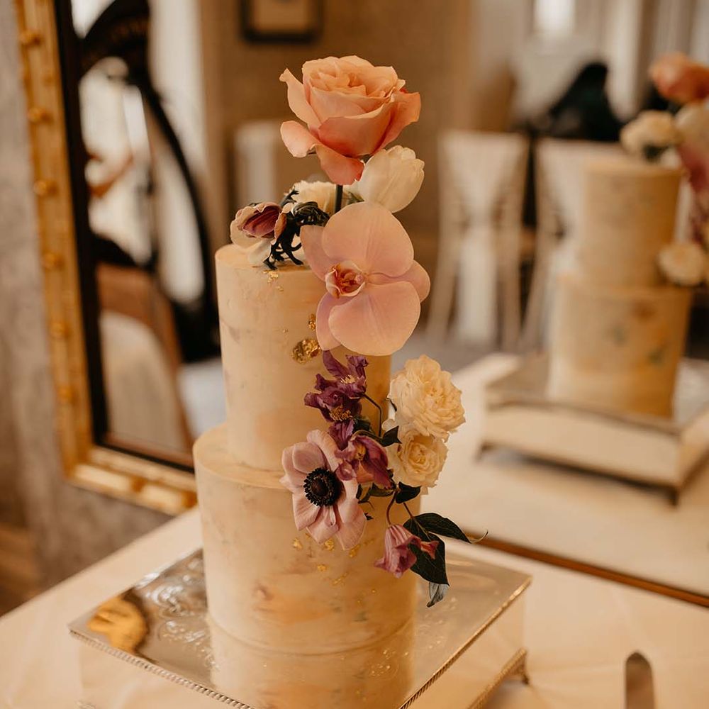 Two tiered cream wedding cake with neutral coloured rose and foliage decorations 