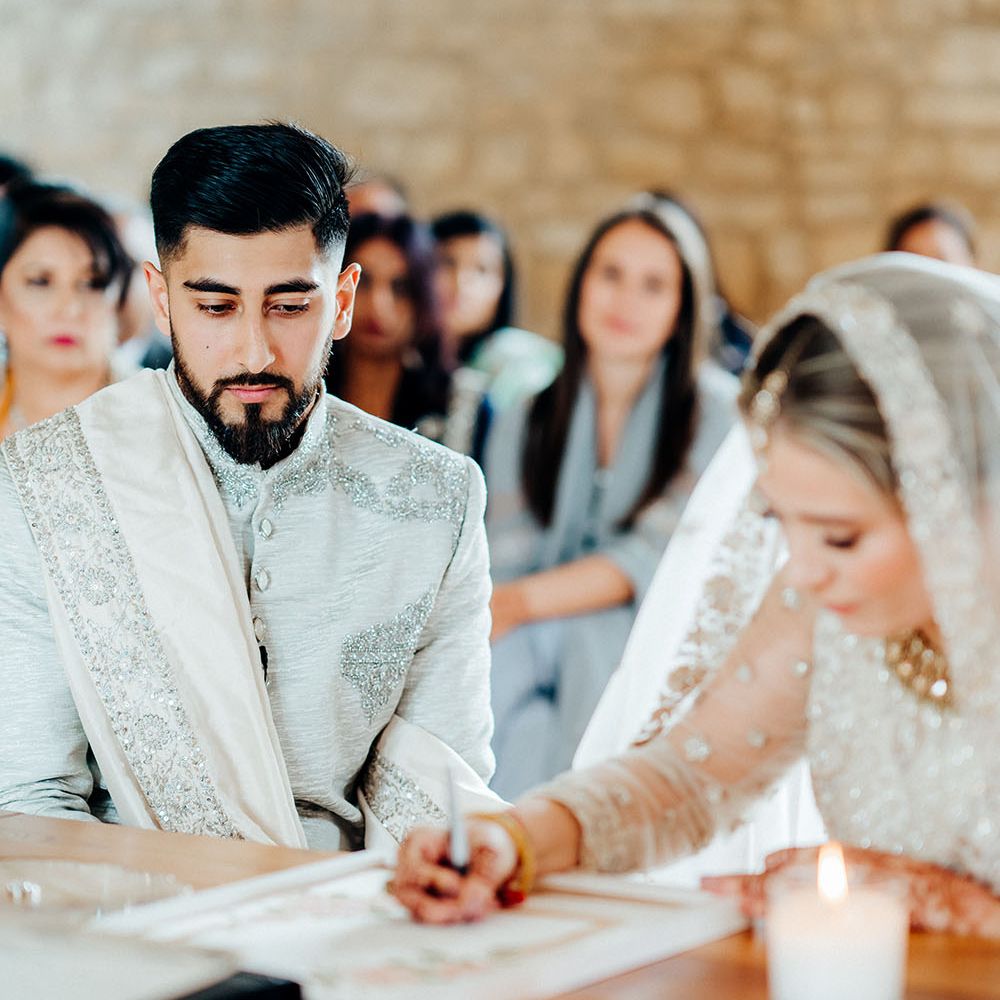 Bride & groom sign marriage certificate during their wedding ceremony at The Barn At Upcote 