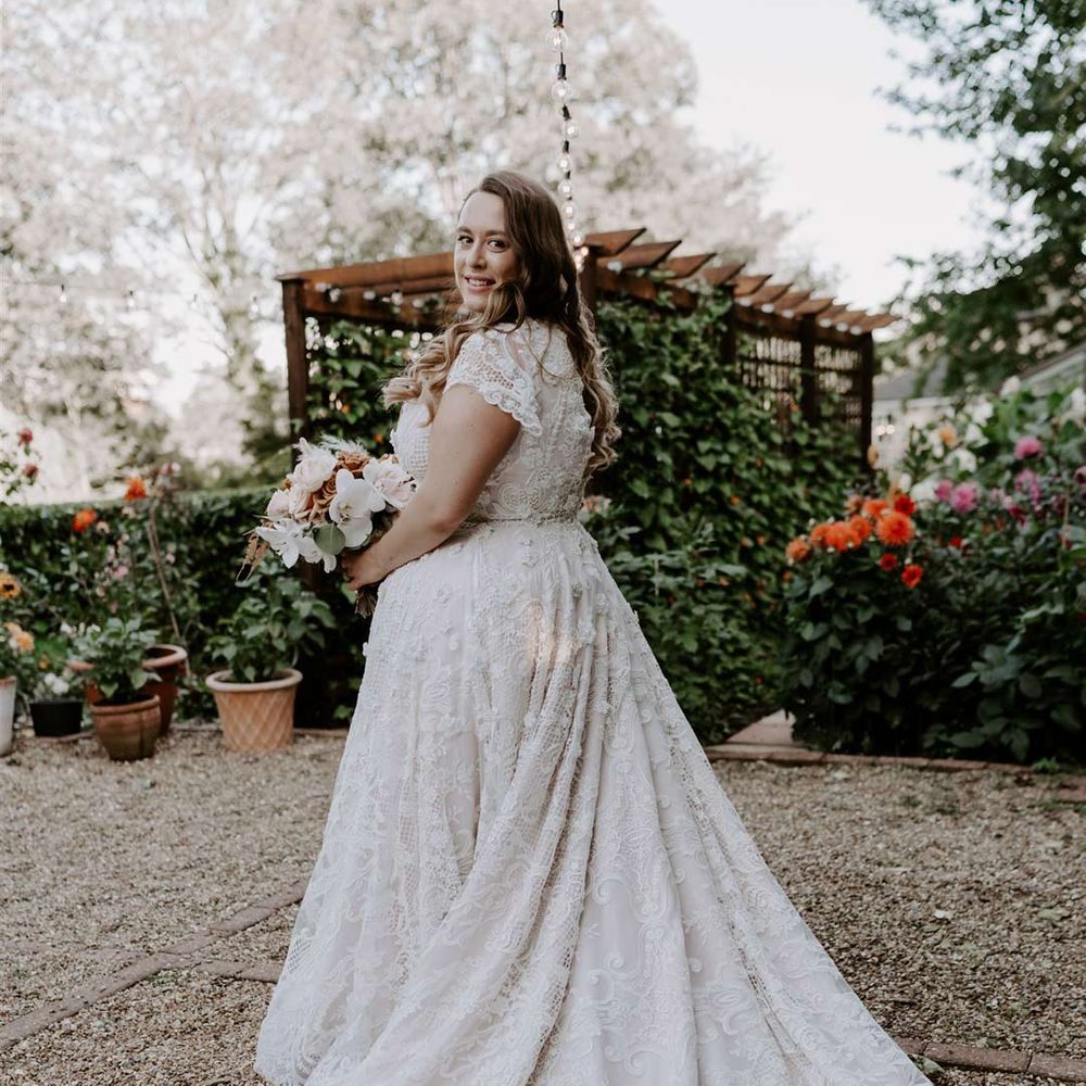Bride in DIY short sleeve deep v neck lace wedding dress with full train