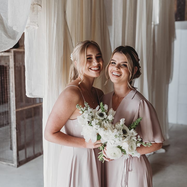 Bridesmaids with white flower bouquets in pale pink dresses