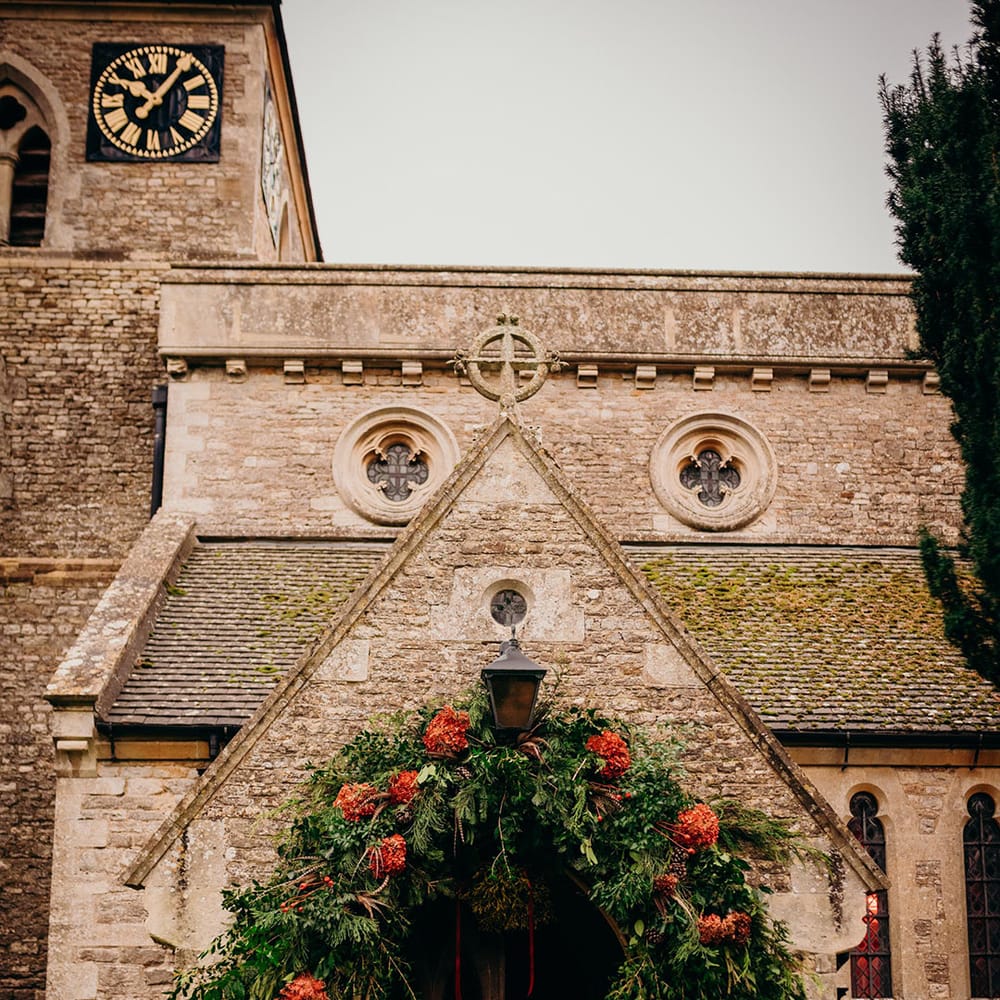 Church with large foliage and red flower floral arch at winter wedding
