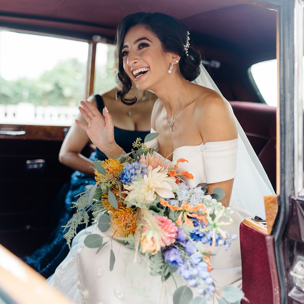 Bride holds colourful bridal bouquet and wears her hair pinned back with peal hair accessory 