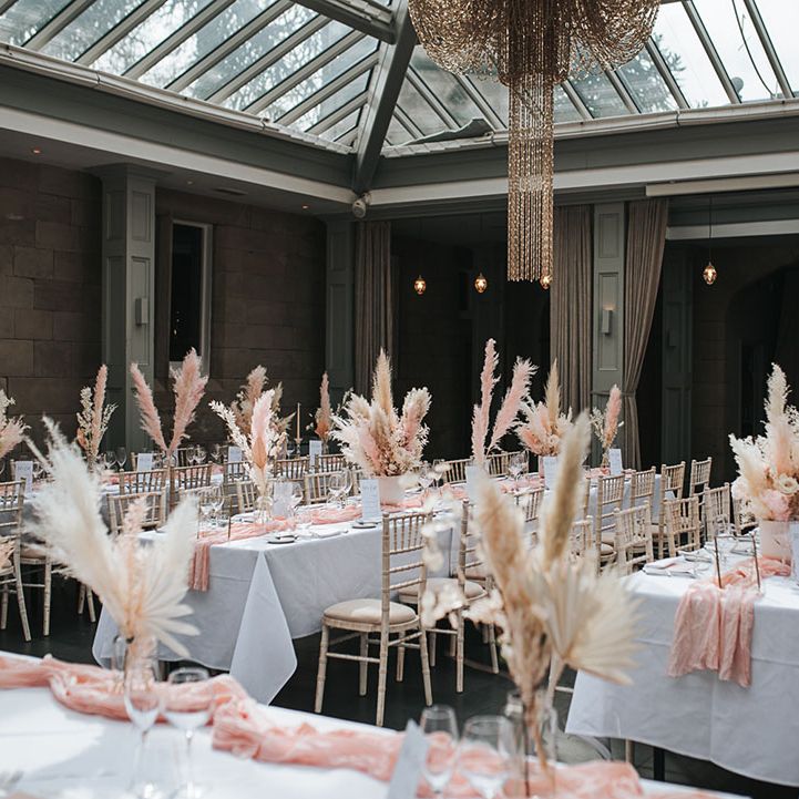 Hampton Manor wedding venue with tables with white tablecloths, pink table runners and white and pink pampas grass centrepiece decor 