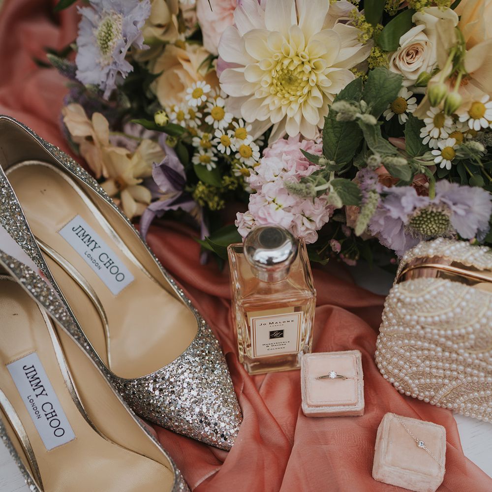 Sparkly pointed Jimmy Choo wedding shoes with Jo Malone perfume with the pastel flower bridal bouquet and pearl clutch with jewellery 