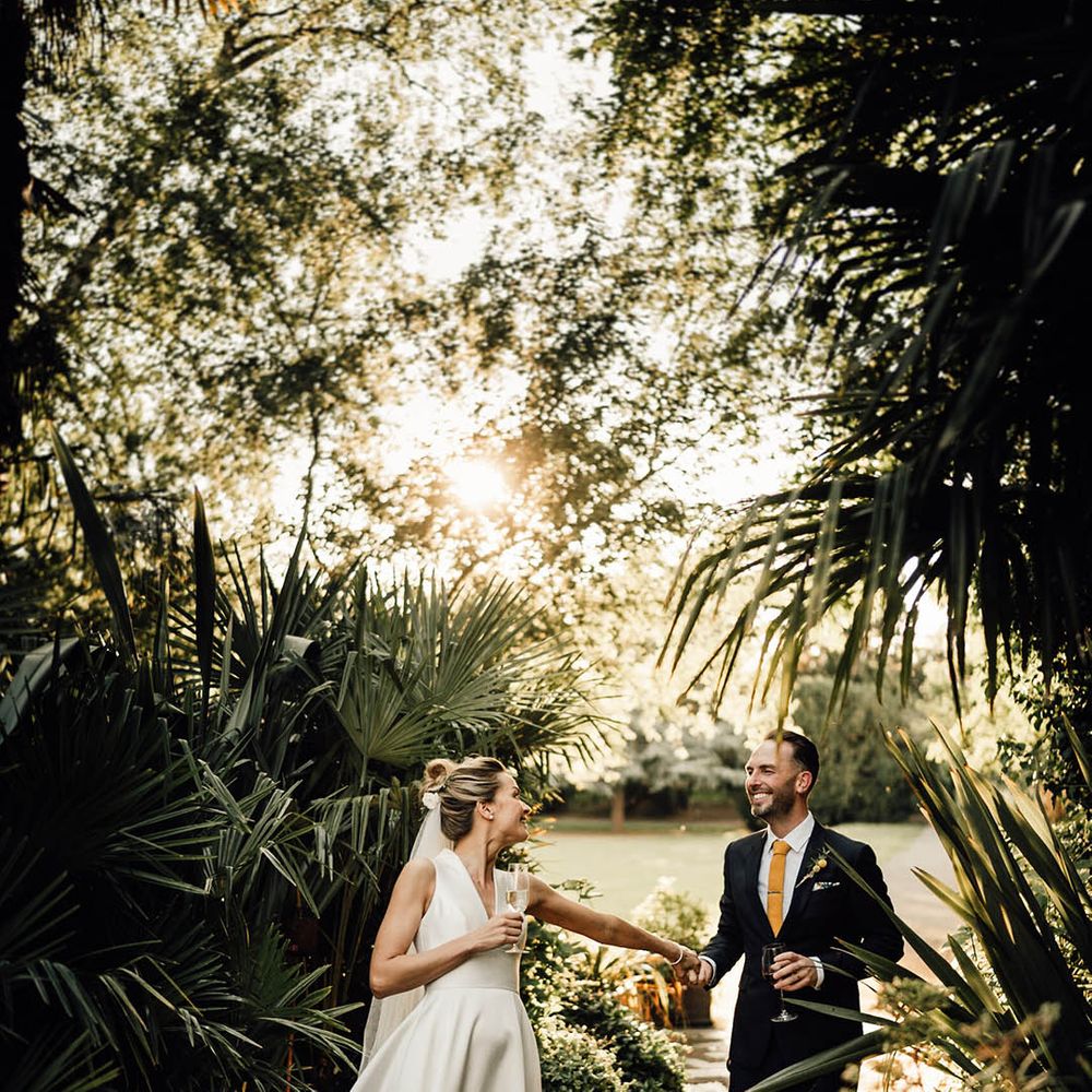 Bride in Sheila Harding wedding dress walking along with groom at country house wedding in Surrey 