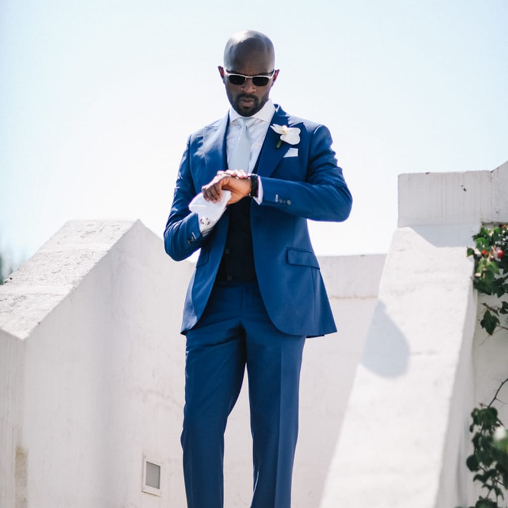 Groom waiting for his bride for their wedding in Puglia Italy wearing sun glasses and three piece blue suit 