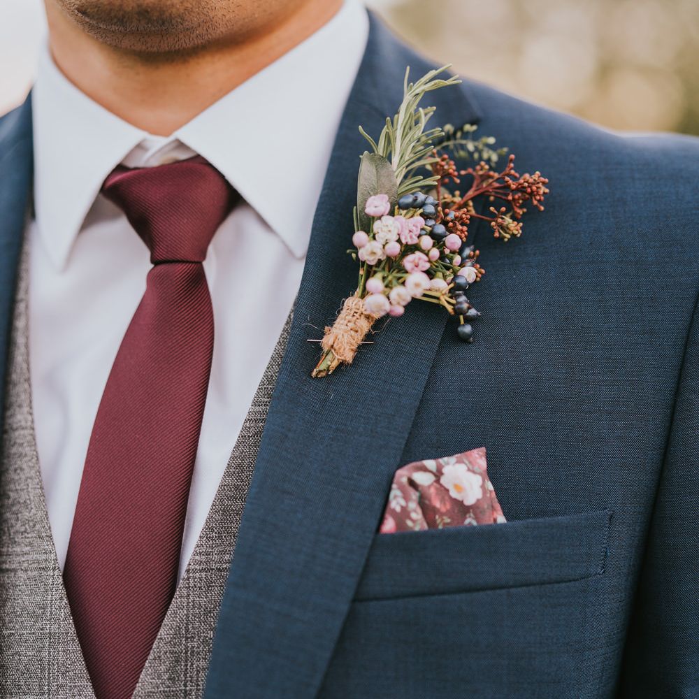 Groom wears colourful floral buttonhole tied with brown string