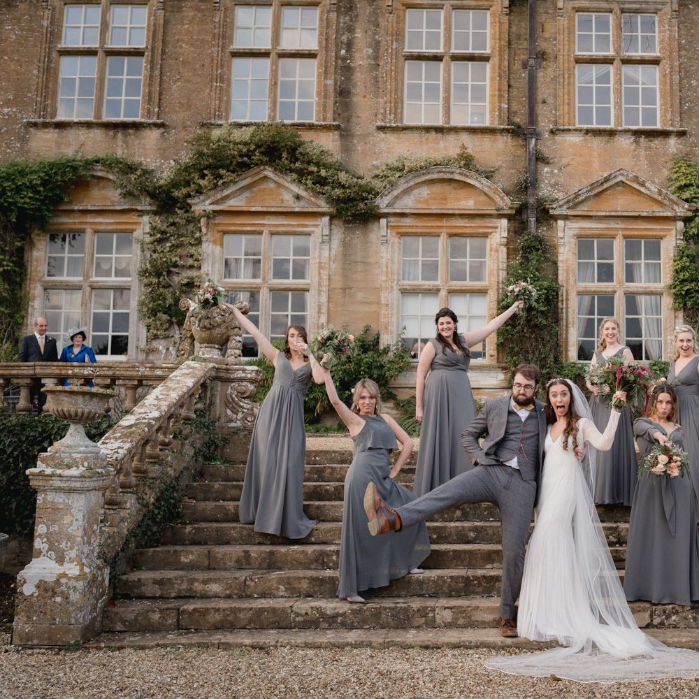 Bride and groom outside Brympton House with their bridesmaids wearing dark grey bridesmaid dresses