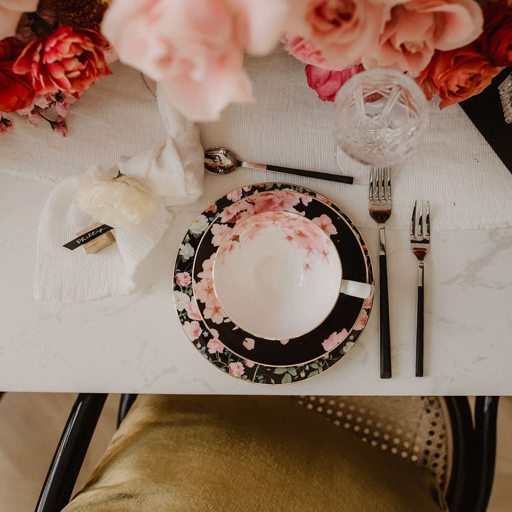 White tableware with black and pink floral design, silver and black cutlery and peach wedding flowers