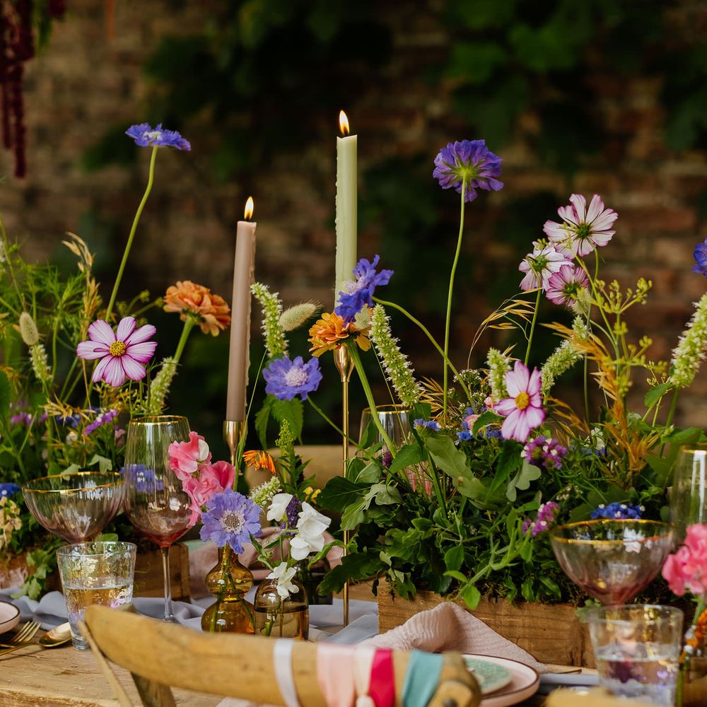 Wildflower plant box centrepiece flowers with flower stems in vases, and colourful taper candles for fiesta theme wedding 
