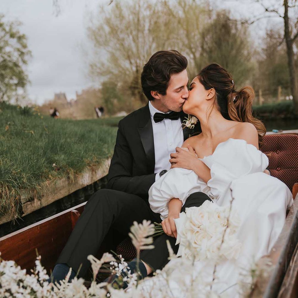 Bride and groom kissing in a boat at their Oxford wedding 