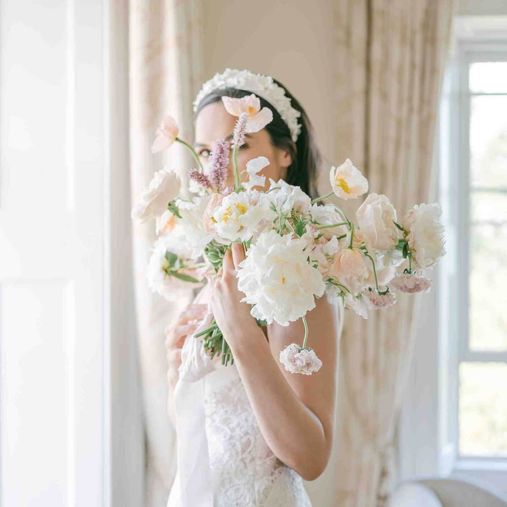 Delicate summer wedding bouquet with roses, peonies, Icelandic poppies, sweet peas, scabious, foxglove, and snapdragons