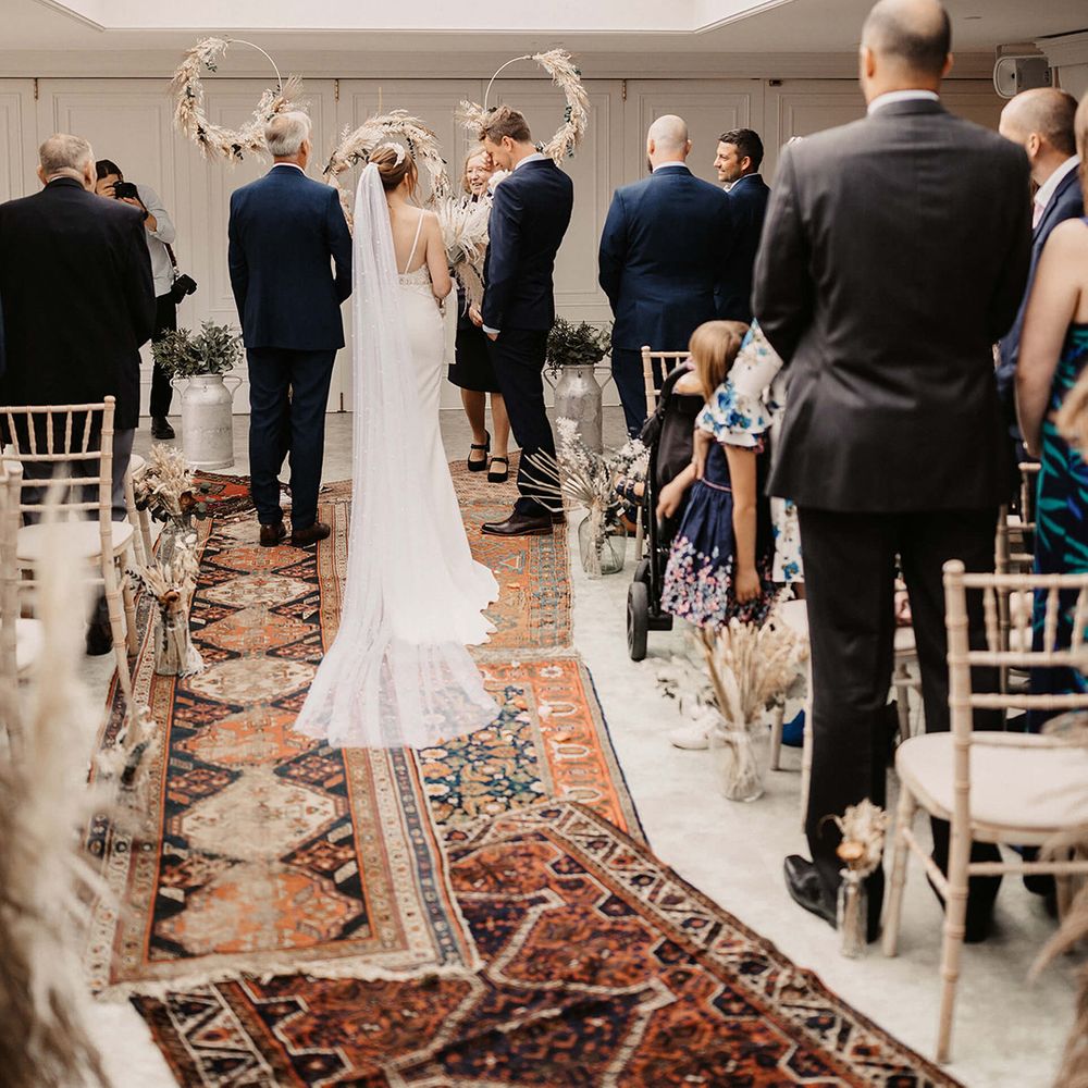 Bride & groom stand at the end of the aisle on their wedding day