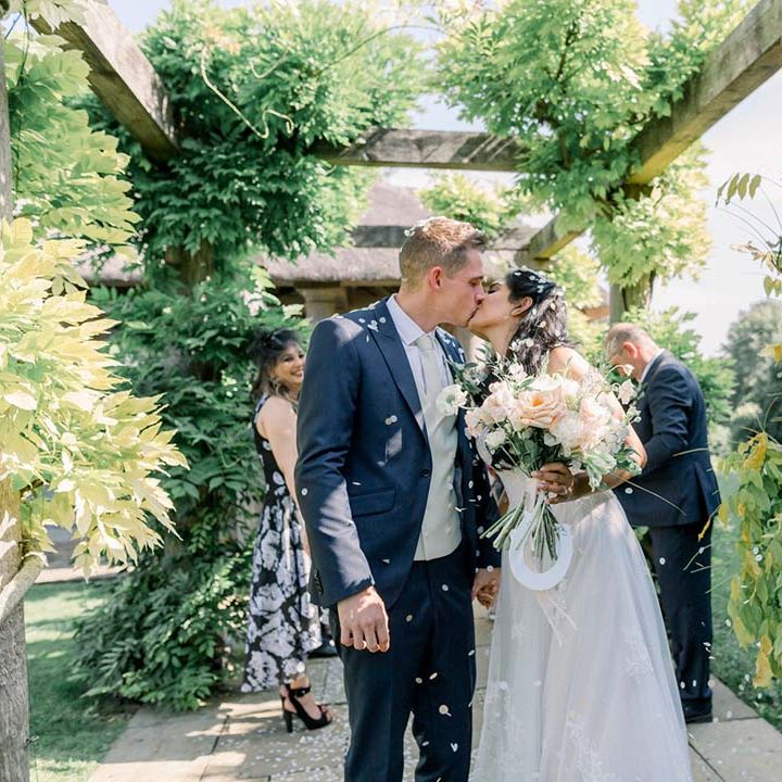 Bride & groom kiss under pergola on their wedding day