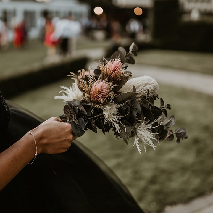 Bride holds pink and white floral bouquet complete with green foliage