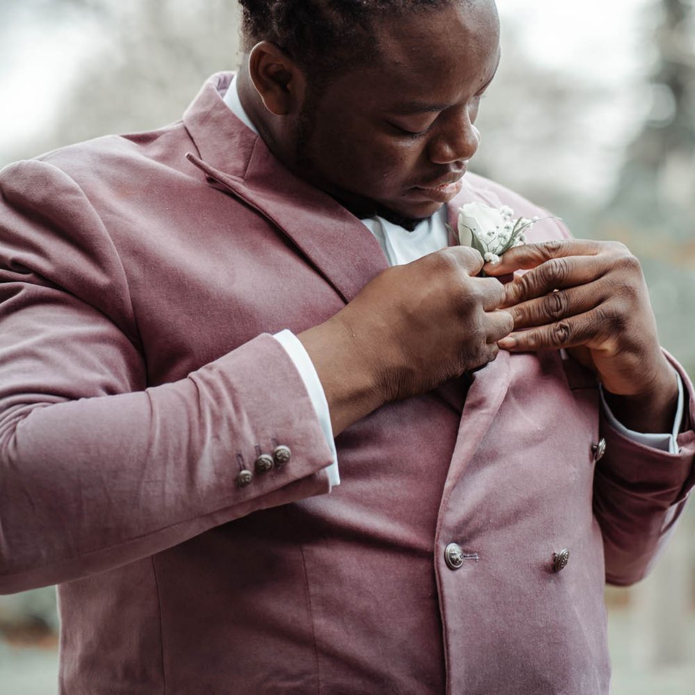 Groom applies floral buttonhole on his wedding day