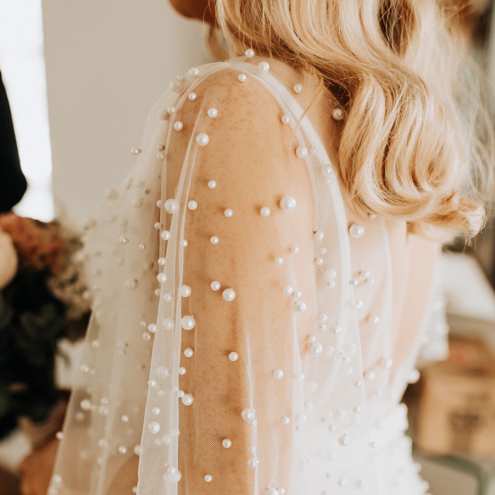 Bride in white wedding dress with mesh pearl encrusted sleeves 