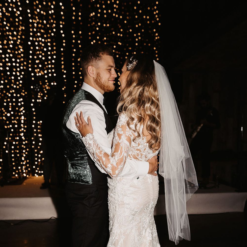 bride and groom share their first dance with groom in paisley waistcoat and bride in ruched lace wedding dress 