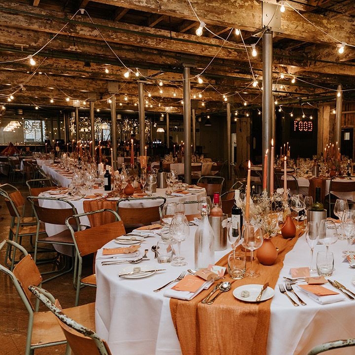 Table settings for autumnal wedding with orange and warm brown coloured vases, candles, runners, napkins and flowers