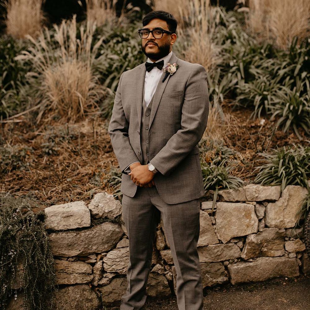 Groom in grey suit, black bow tie and mixed neutral boutonniere at The Petersham Hotel