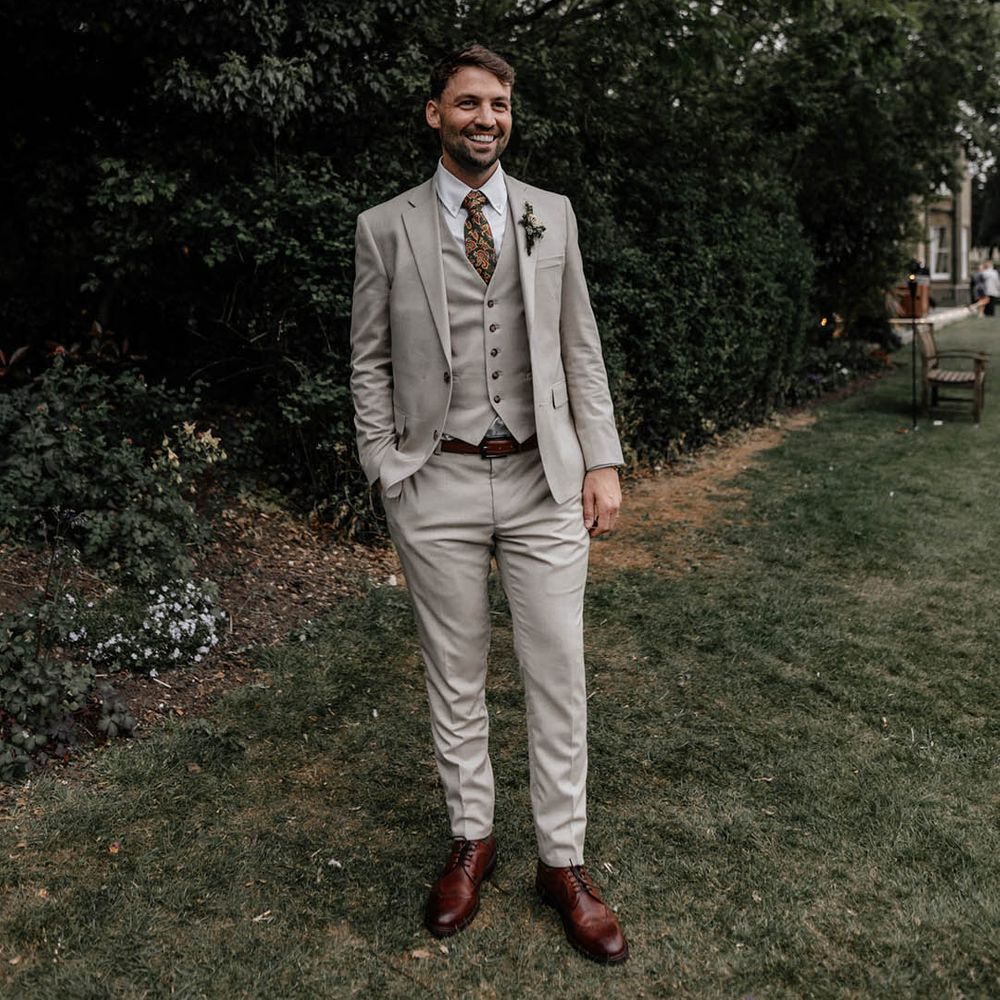Groom in a stone coloured three piece suit with paisley tie 