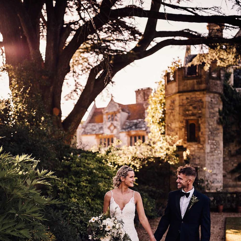Bride and groom hold hands walking outside of their historic wedding venue 